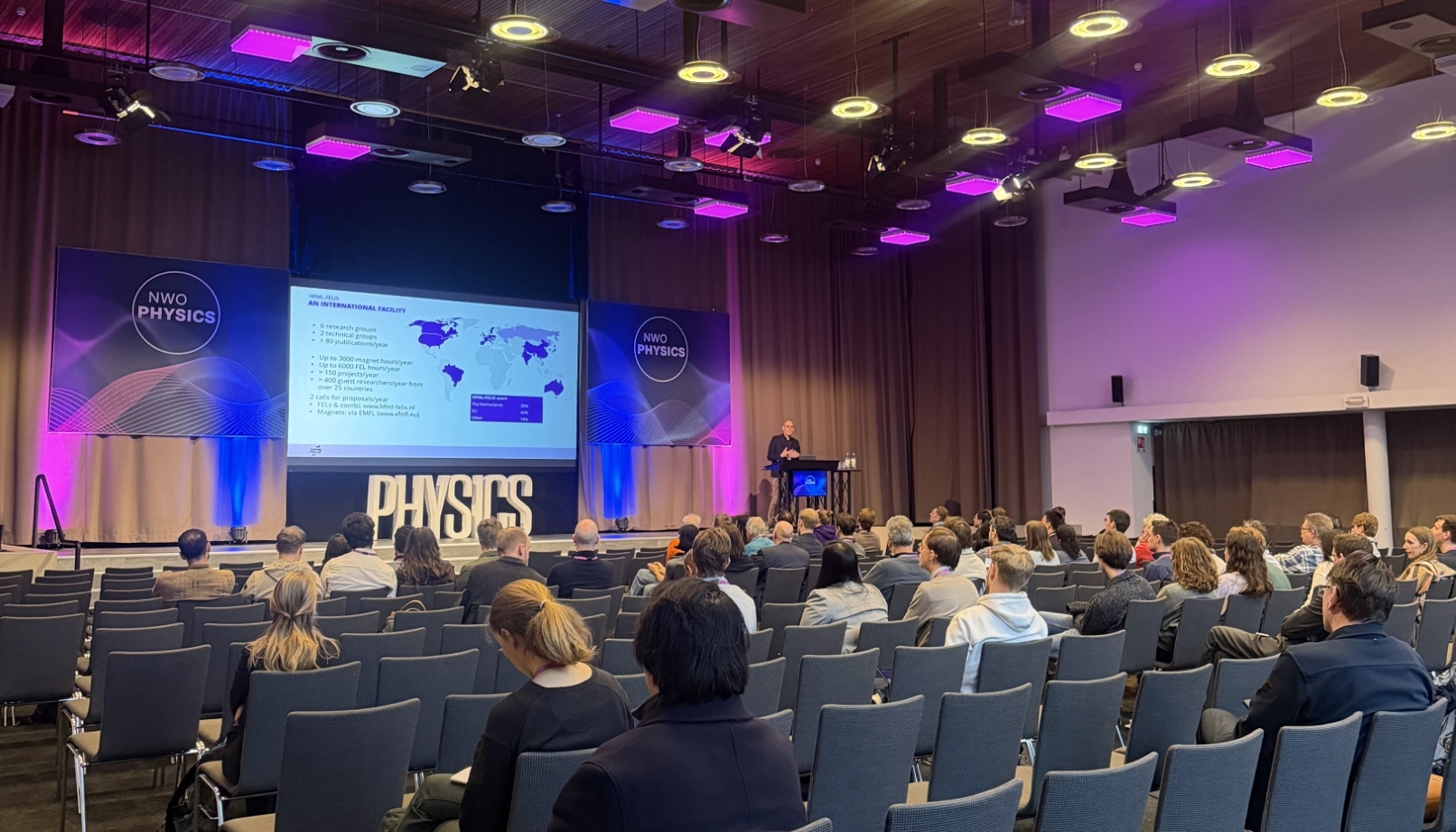 An overview picture of director Marc Baldus on stage giving a talk to the audience at NWO Physics 2026.